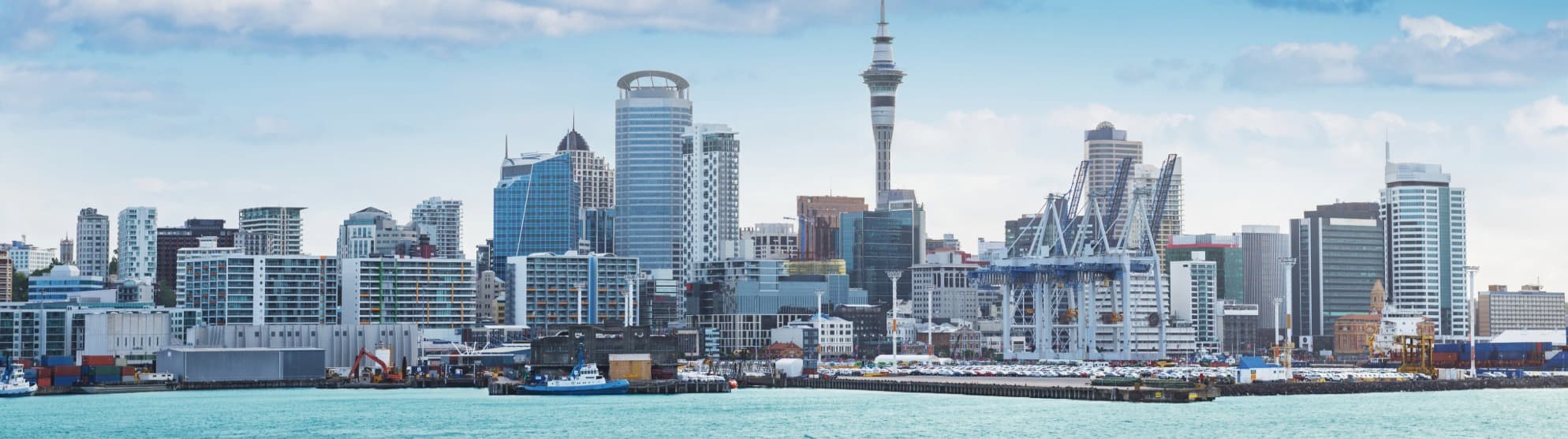 Panorama der Skyline von Auckland mit dem Sky Tower und dem Hafen für den sicheren Überseeumzug nach Neuseeland mit DACHSER & KOLB.