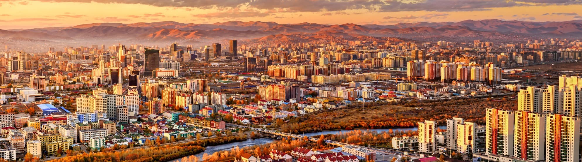 Panoramablick auf Ulaanbaatar in der Mongolei mit Skyline, Fluss und Bergen bei Sonnenuntergang