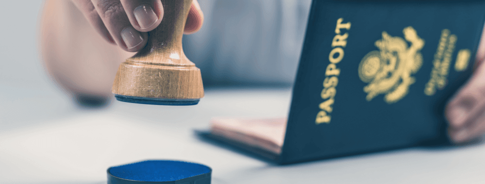 Hand mit Stempel vor Reisepass als Symbol für Einreise und Dokumente bei einem Umzug nach Finnland