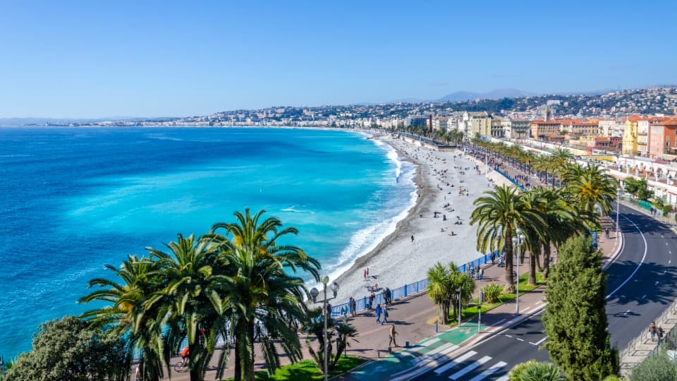 Mittelmeerküste in Nizza mit Strand, Palmen und blauem Meer