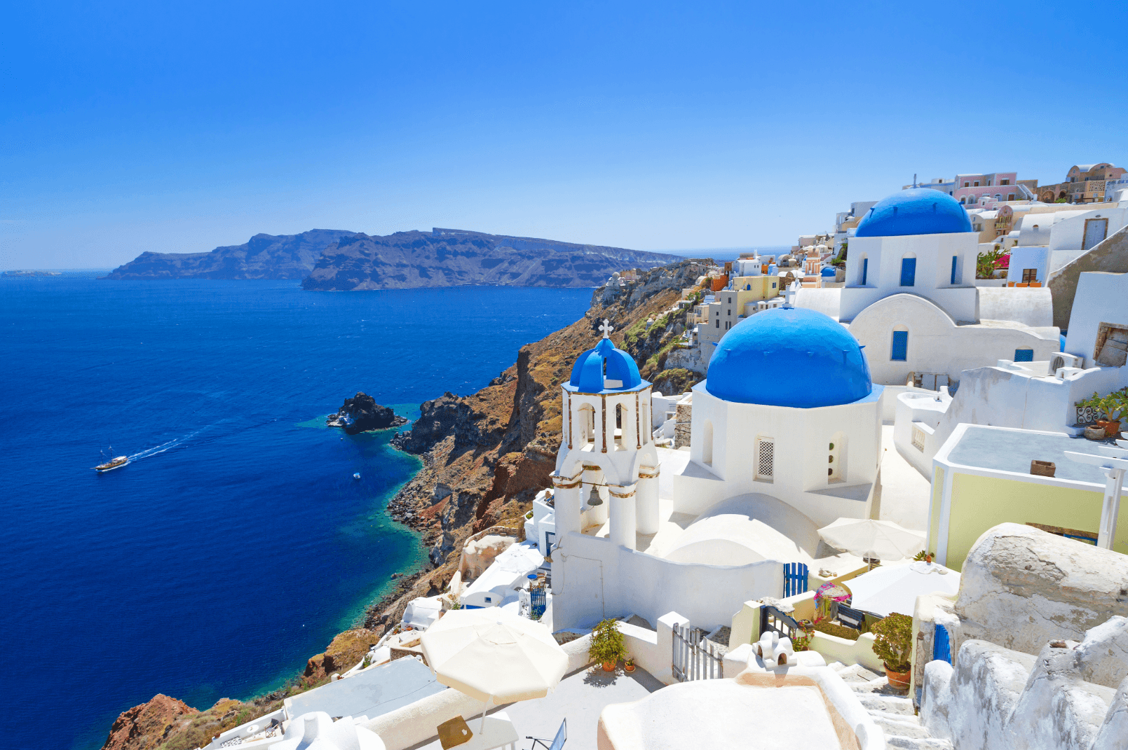 Weiße Häuser und blaue Kuppeln auf Santorin mit Blick auf das Ägäische Meer