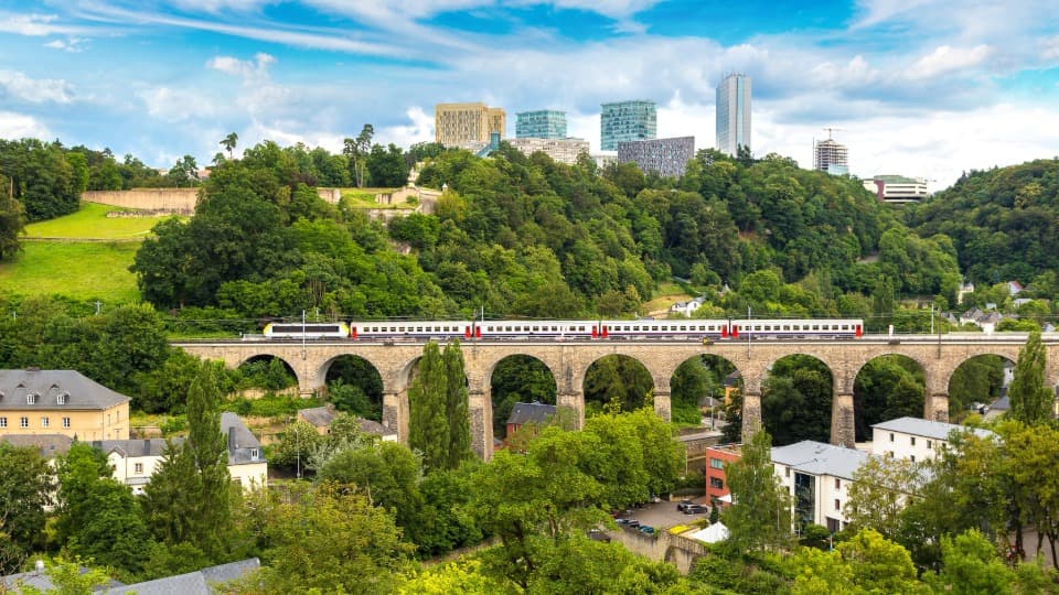 Kostenloser Nahverkehr in Luxemburg: Ein Zug überquert das Viadukt vor der Kulisse der EU-Institutionen und modernen Bürogebäude in Luxemburg-Stadt.