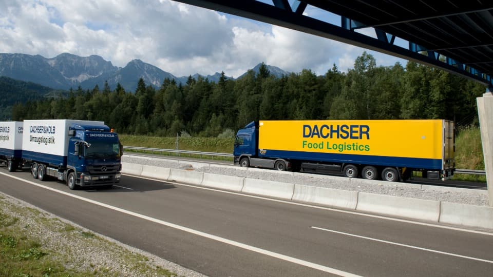 Ein Umzugs-LKW von DACHSER & KOLB und ein LKW der DACHSER Food Logistics auf der Autobahn vor einer Bergkulisse zur Veranschaulichung der Netzwerkkraft.