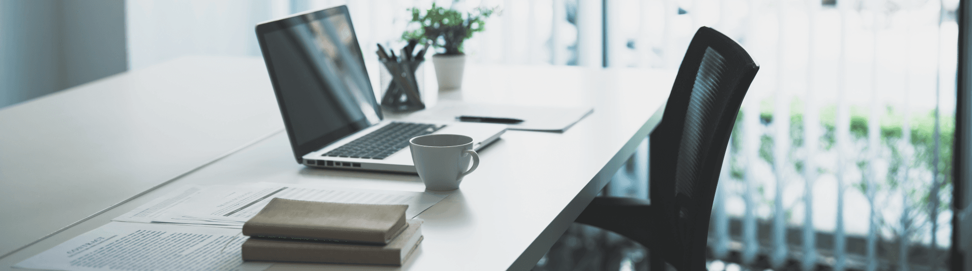 Heller Home Office Arbeitsplatz nach Umzug mit Laptop, Kaffeetasse, Büchern und Stuhl. Einrichtungsideen für modernes Arbeiten zu Hause.