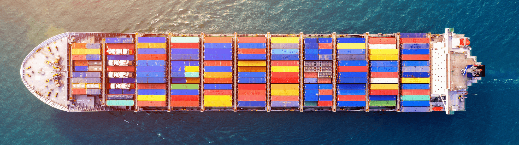Drohnenaufnahme eines riesigen Frachtschiffs voller bunter Container auf dem Meer. Repräsentiert Full Container Load (FCL).
