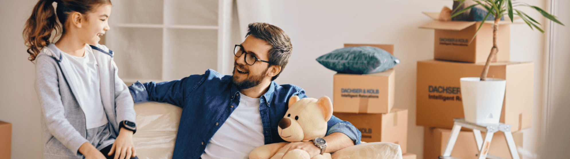Vater und Tochter lachen beim Umzug, umgeben von DACHSER & KOLB Kartons – Qualität durch FIDI-Zertifizierung.