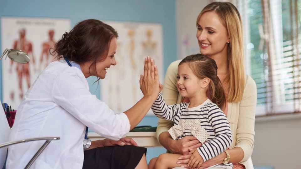 Ärztin bei der Untersuchung eines Kindes – Informationen zur Krankenversicherungspflicht und Familienabsicherung in Deutschland.