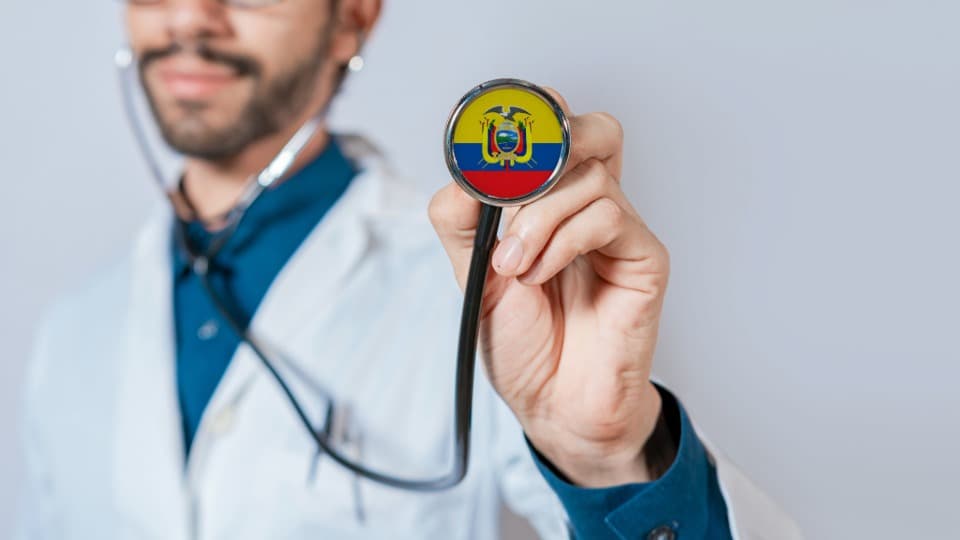 Ein ecuadorianischer Arzt hält ein Stethoskop mit der Landesflagge zur Kamera als Zeichen für das Gesundheitssystem in Ecuador