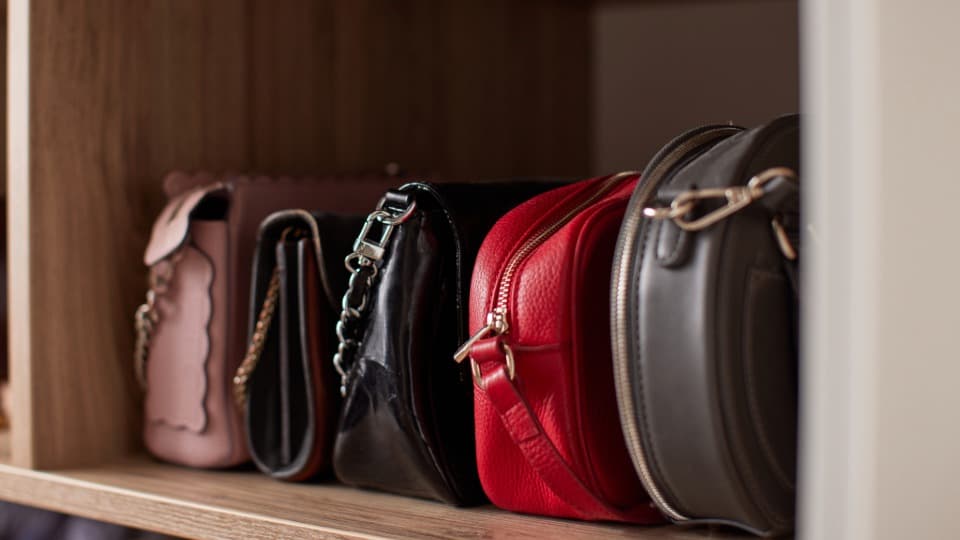 Eng aneinandergereihte Handtaschen im Regal, die vor dem Transport durch DACHSER & KOLB vor Reibung, Licht und Feuchtigkeit geschützt werden müssen.