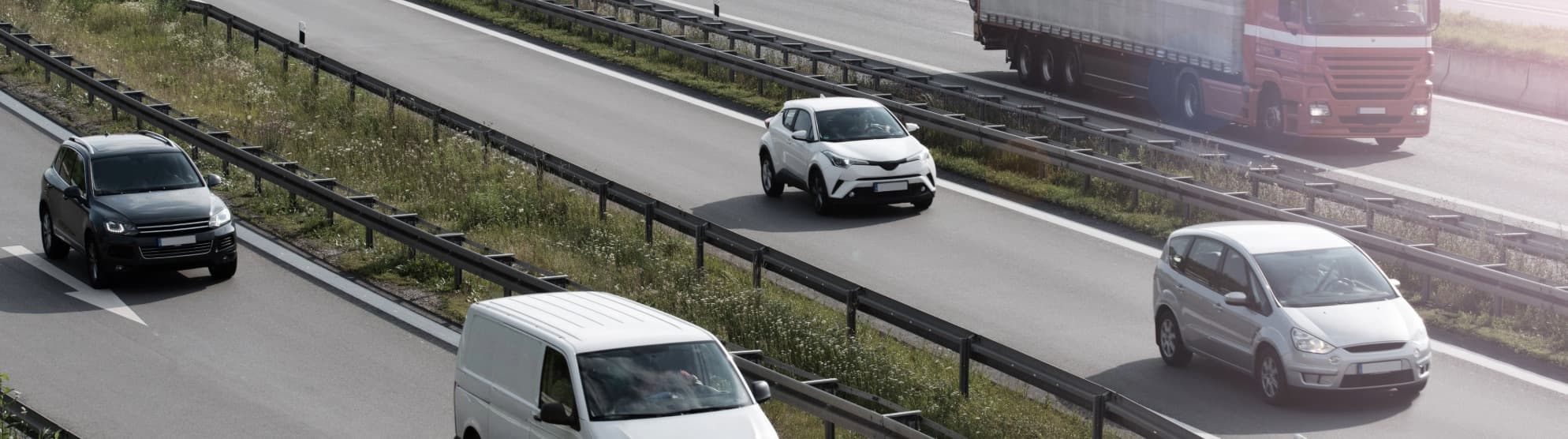 Blauer Lkw fährt auf Landstraße durch Berge – Symbol für Transportdauer beim Umzug.