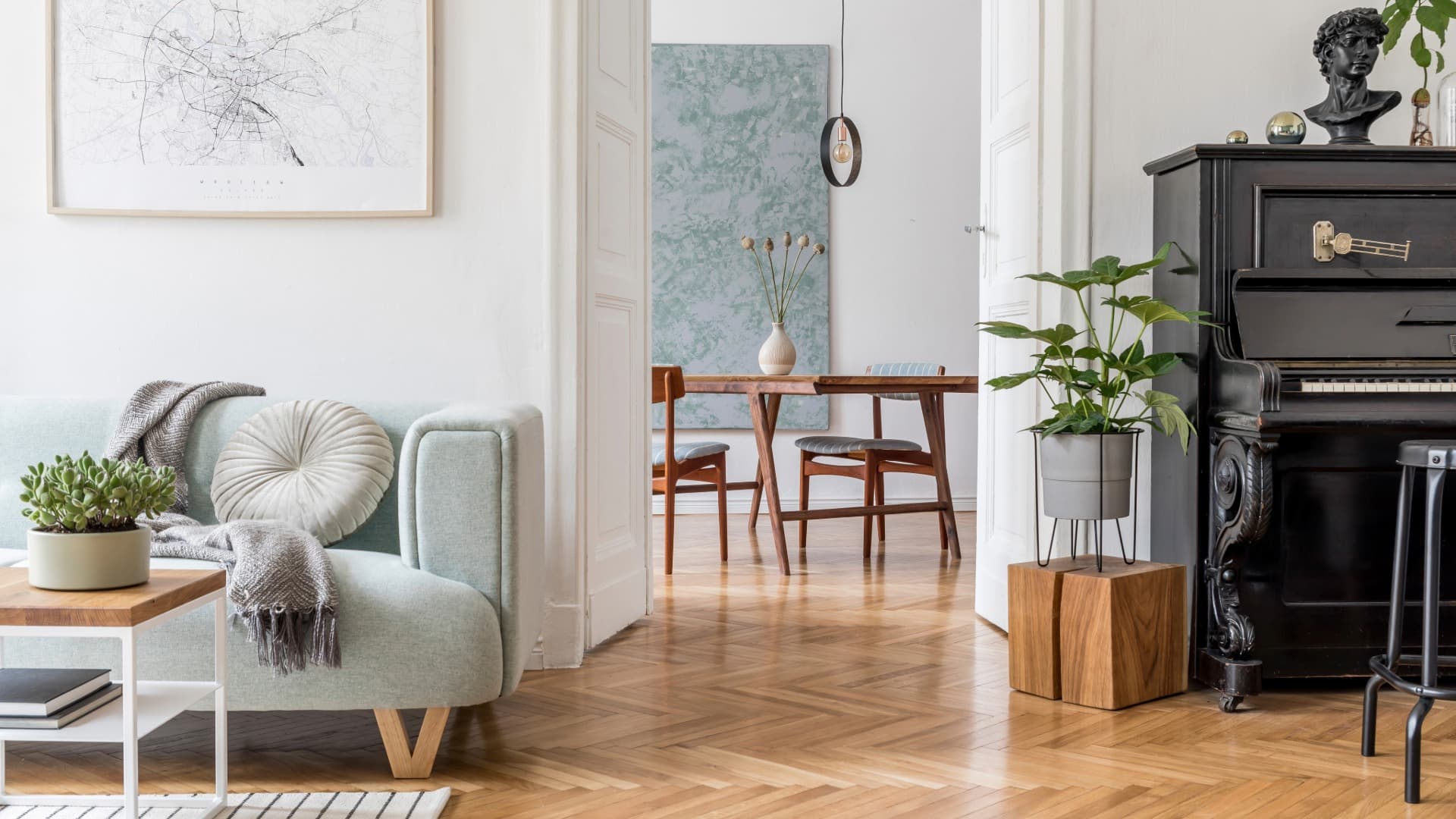 Helles Wohnzimmer mit Sofa, Esstisch und Klavier in einer stilvoll eingerichteten Altbauwohnung
