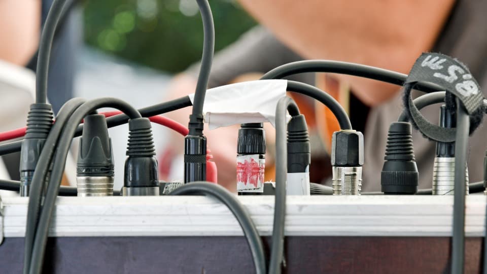 Mehrere eingesteckte Audiokabel mit einer handschriftlichen Beschriftung als Beispiel für das Sichern der Systemlogik vor dem Umzug mit DACHSER & KOLB.