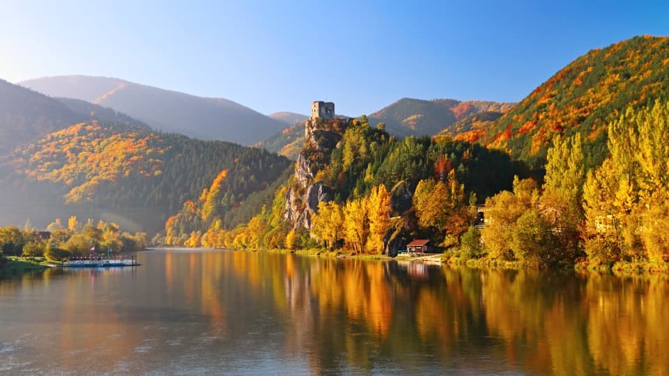 Eine Landschaft in der Slowakei mit Gewässer, Wäldern und Bergen mit einer Burgruine