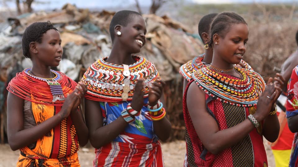 Kultur in Kenia: Mehrere Kenianer in traditionellen Gewändern klatschen in die Hände