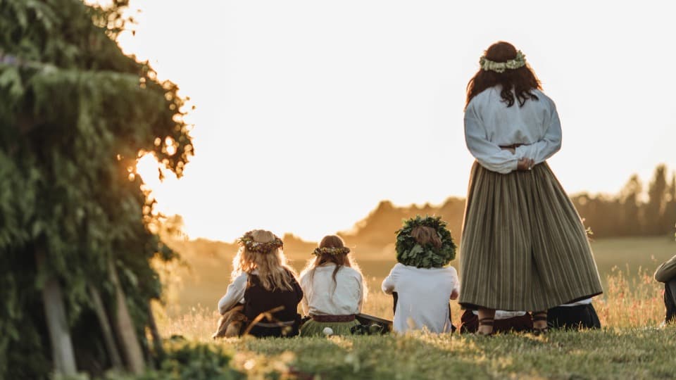 Frauen und Kinder in lettischen Volkstrachten mit Blumenkränzen bei der Mittsommerfeier Jāņi – ein Symbol für die tief verwurzelte Kultur Lettlands