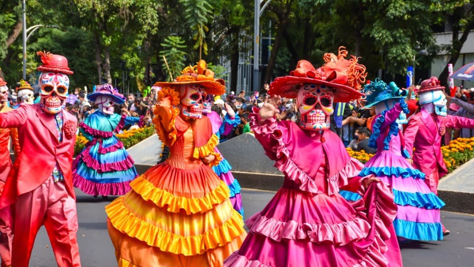 Verkleidete Menschen mit Totenkopfmasken feiern in Mexiko den Día de Muertos