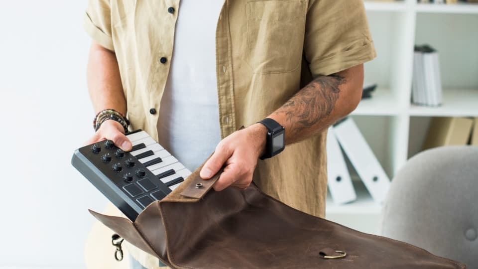 Eine Person packt ein Keyboard und einen MIDI-Controller für den sicheren Umzug mit DACHSER & KOLB in eine Tasche.