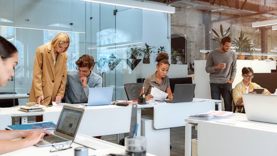 Mitarbeiter in einem modernen Co-Working-Space arbeiten flexibel an Laptops.