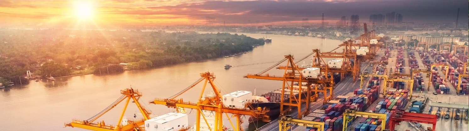 Containerhafen am Fluss bei Sonnenaufgang – Symbol für POE (Port of Entry) als zentraler Einfuhrhafen.