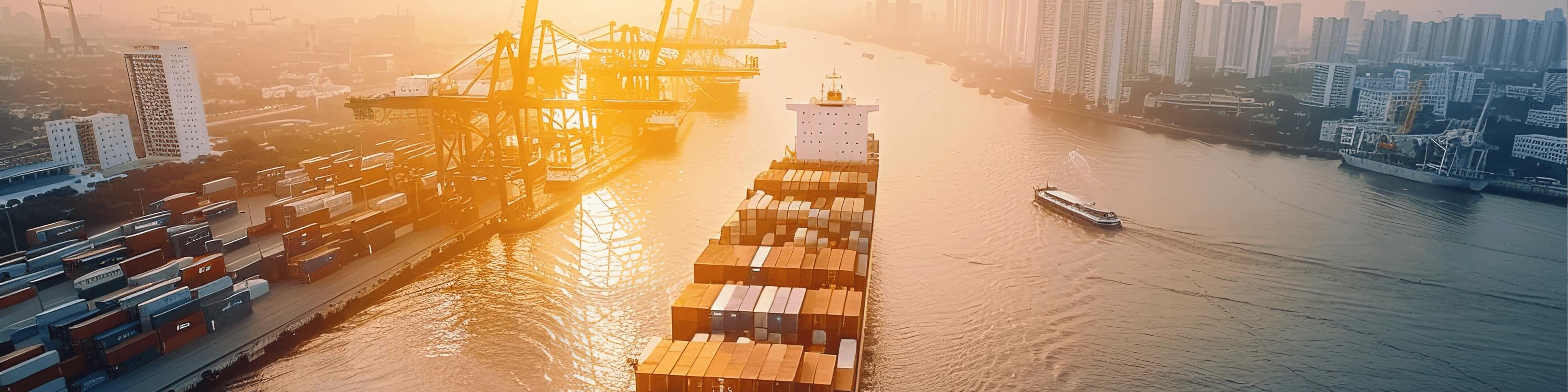 Containerschiff einer Reederei navigiert durch einen Hafenkanal mit Kranen und Stadt im Hintergrund.
