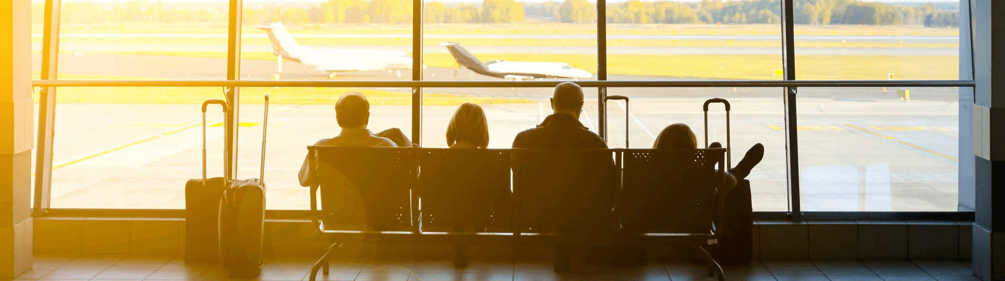Reisende mit Koffern am Flughafen warten auf ihren Flug – Symbolbild für internationalen Relocation Service