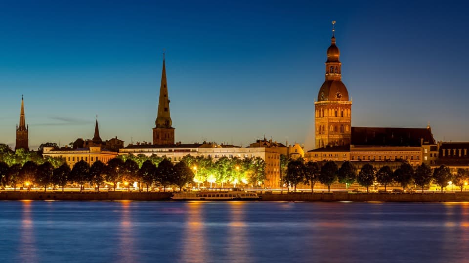 Die beleuchtete Silhouette der Altstadt von Riga bei Nacht – ein Zeichen für die Stabilität und Sicherheit am Auswanderungsziel Lettland.