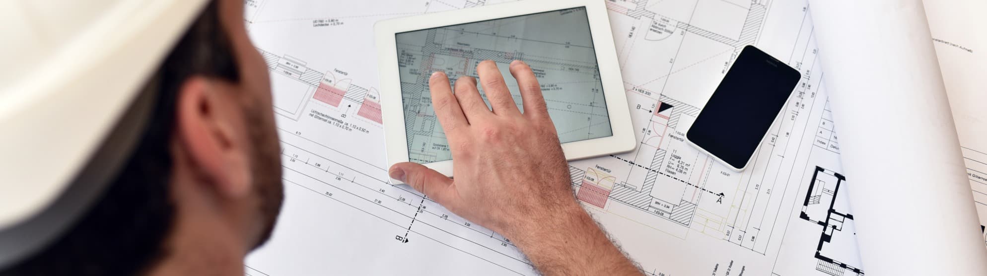 Projektleiter analysiert den Grundriss auf einem Tablet fuer die lueckenlose Standortverlagerung.