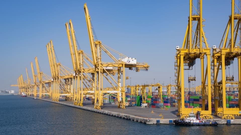 Großer Containerhafen Jebel Ali in den VAE mit gelben Hafenkränen und Containern für den Überseeumzug mit DACHSER & KOLB.