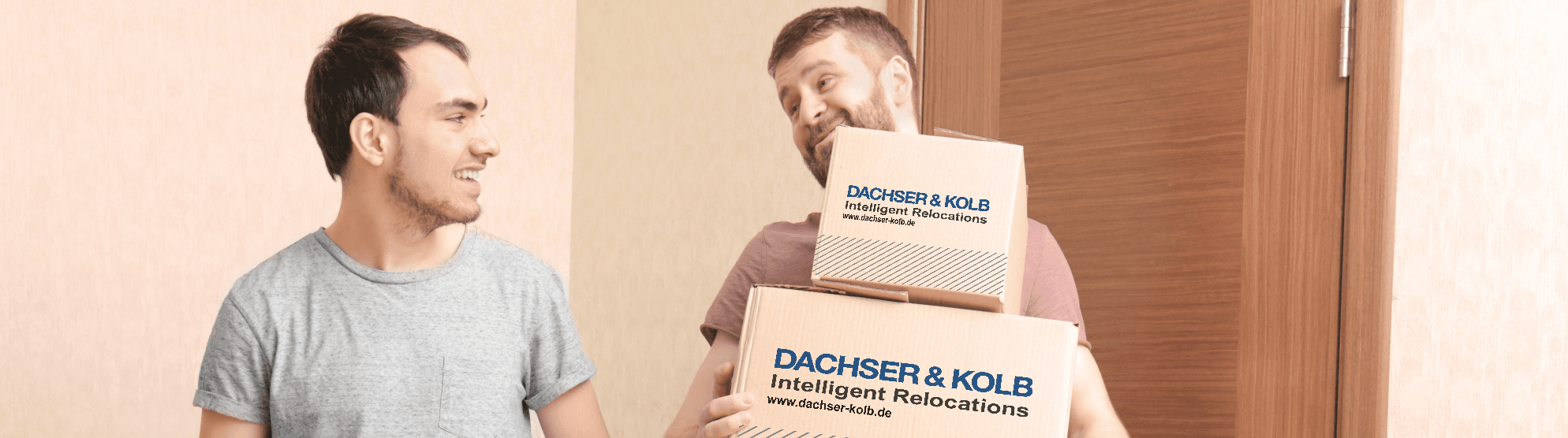 Zwei Männer tragen lachend Umzugskartons – Beispiel dafür, wie man Umzugskartons richtig packen und transportieren kann.
