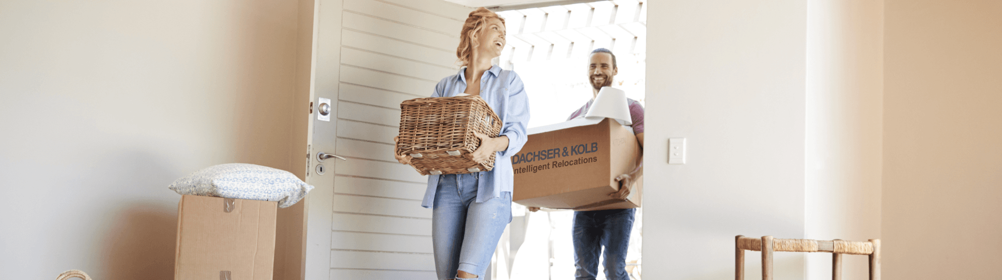 Paar trägt Umzugskartons und Körbe in neues Zuhause – Tipps und Hilfe im Umzugsratgeber