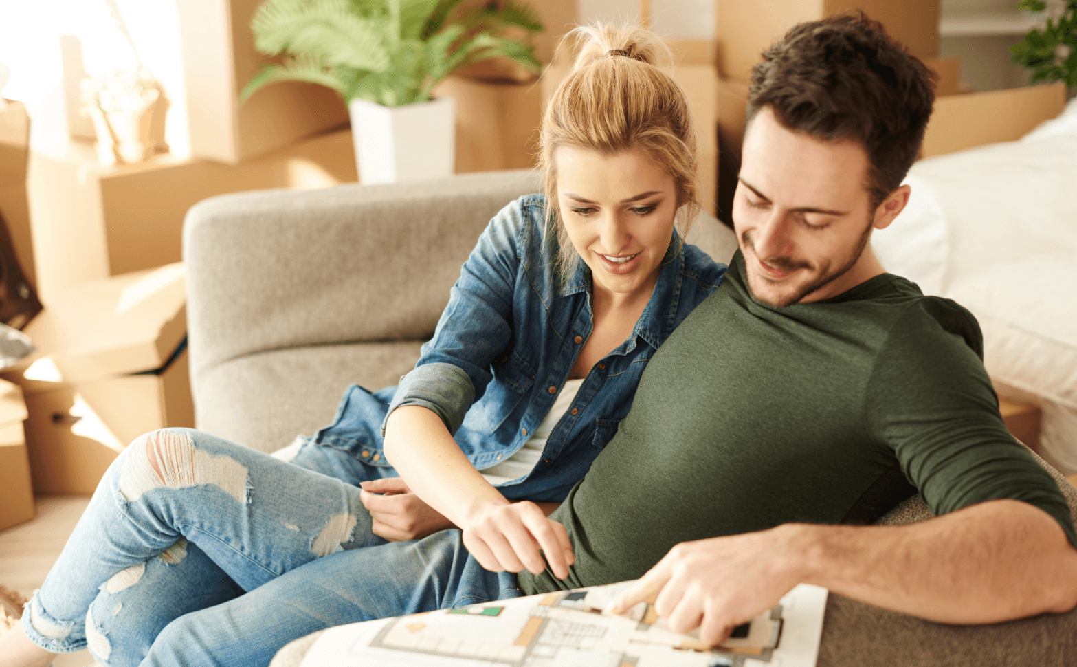 Couple sitting on a sofa planning a VIP relocation for high-profile personalities using a floor plan