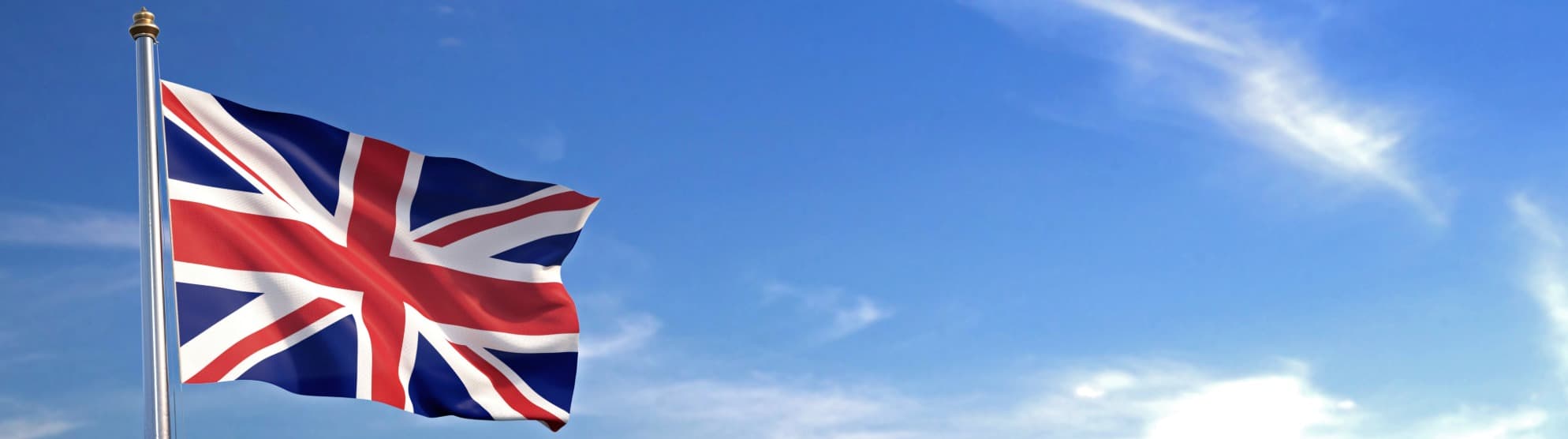 Britische Flagge (Union Jack) an Fahnenmast vor blauem Himmel