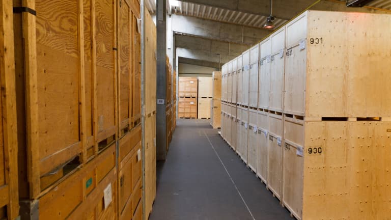 Große Holzkisten zur sicheren Zwischenlagerung von Büroinventar in der sauberen Lagerhalle von DACHSER & KOLB.