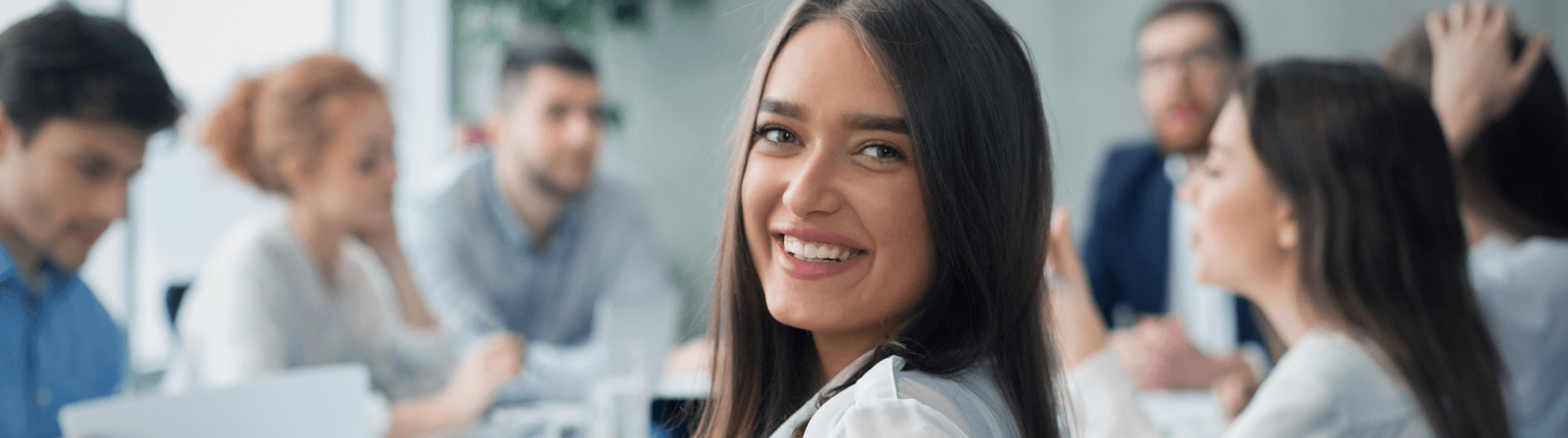 A smiling young woman in the foreground of a group during a training event.