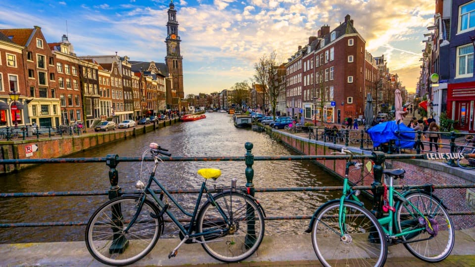 Fahrräder auf einer Brücke über einen Kanal in Amsterdam bei Abendlicht