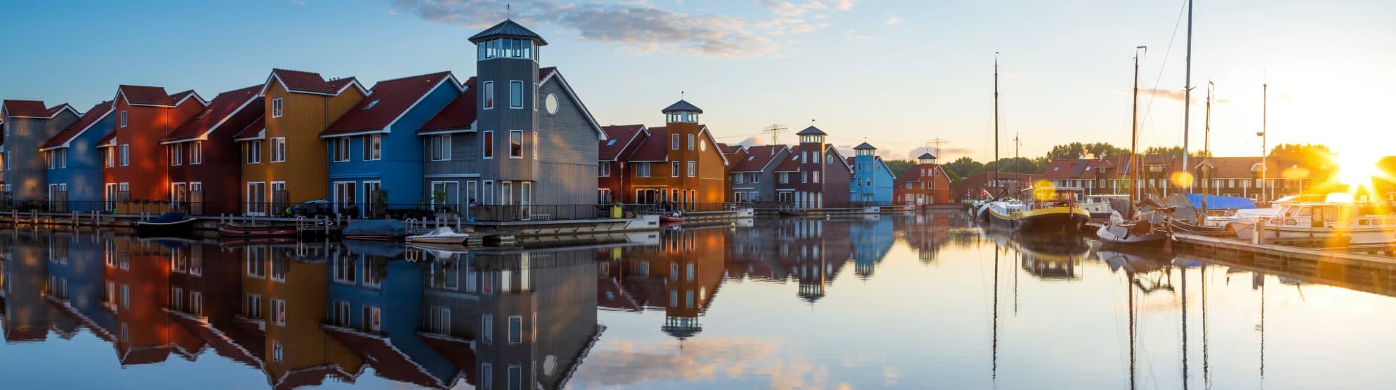 Bunte Häuser und Boote an einem Kanal in den Niederlanden bei ruhigem Abendlicht