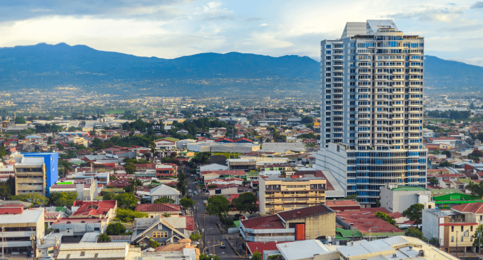 Stadtansicht in Costa Rica mit Hochhaus, Wohnvierteln und Bergen im Hintergrund“
