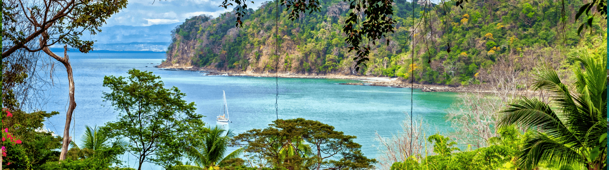 Tropische Bucht in Costa Rica mit türkisfarbenem Wasser, bewaldeter Küste und Segelboot