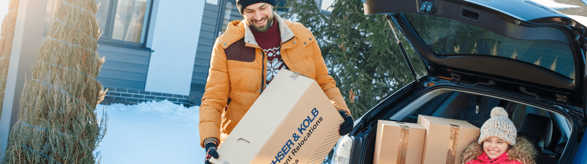 Father and child moving in winter – carrying moving boxes to their new home in snowy weather