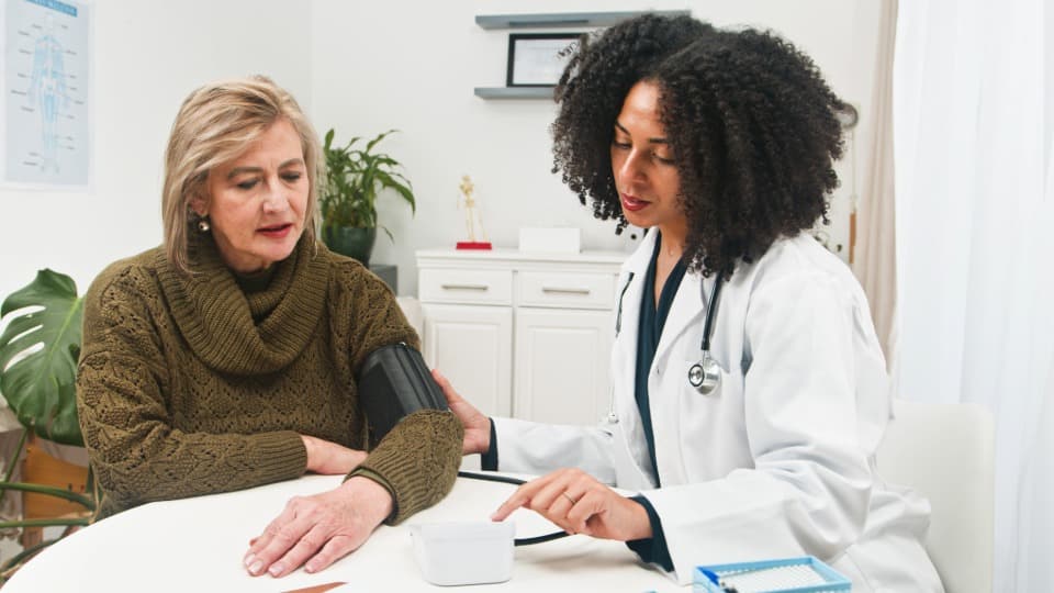 Eine Dominikanische Ärztin ist misst den Blutdruck bei einer Patientin
