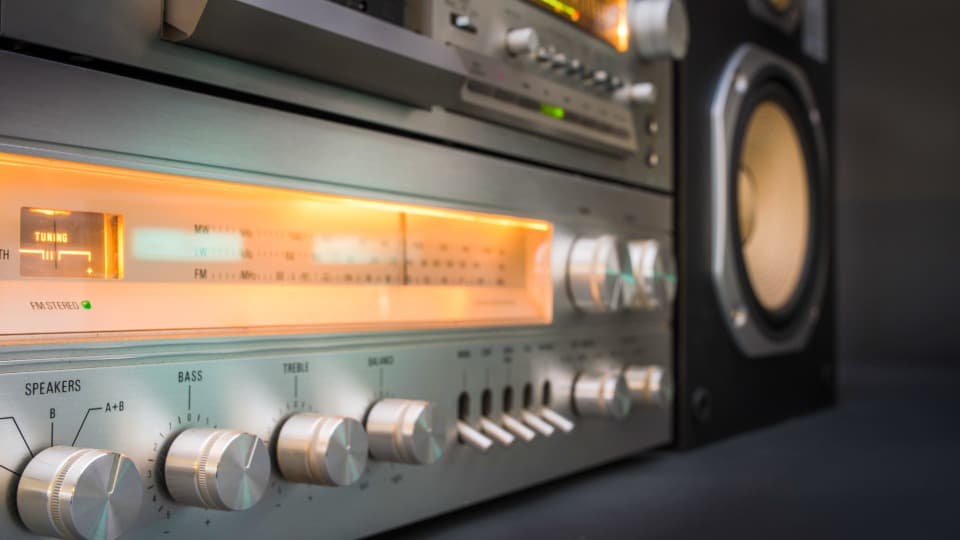 Ein beleuchteter Vintage-HiFi-Verstärker mit silbernen Drehknöpfen und Kippschaltern vor dem geschützten Transport durch DACHSER & KOLB.