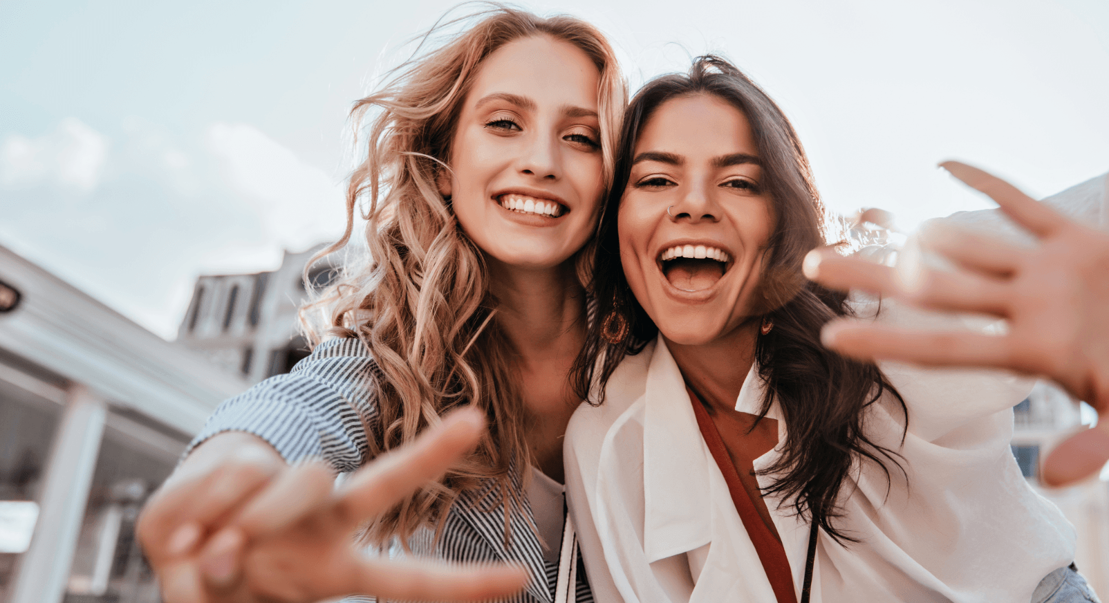 Two cheerful young women take a selfie outdoors. Getting to know the neighborhood after moving.
