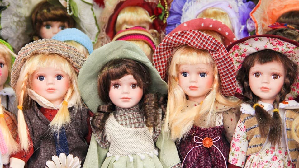 Mehrere wertvolle Porzellanpuppen mit detailreichen Hüten und Kleidern vor der materialgerechten Verpackung für den Umzug mit DACHSER & KOLB.