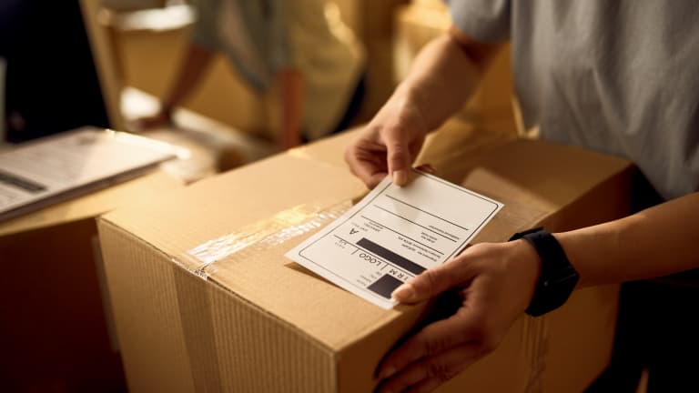 Close-up of a person applying a return label to a package – symbol of fast return service.