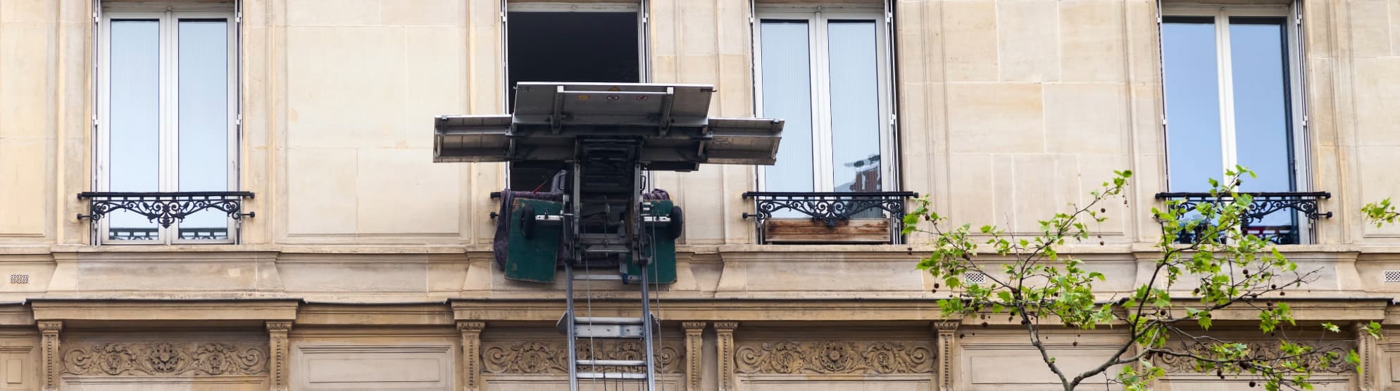 Möbellift hebt Schwergut zum Fenster eines Mehrfamilienhauses – sicherer Transport schwerer Möbel