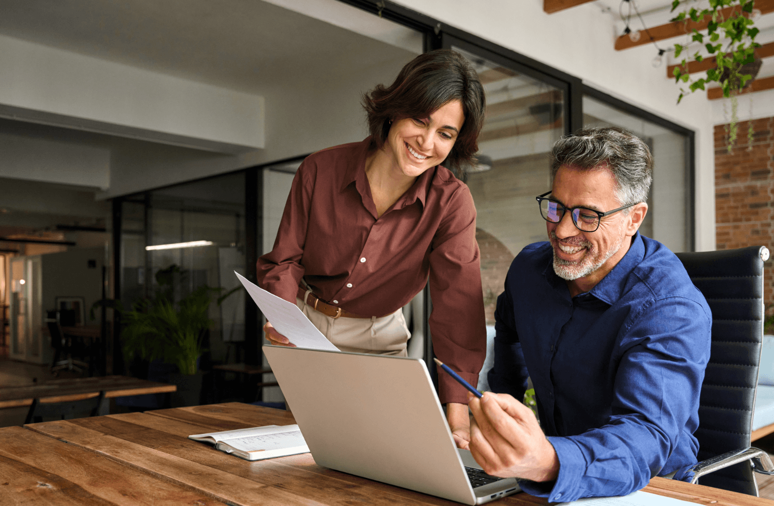 Two colleagues happily discussing special leave for moving at a laptop in a modern office.