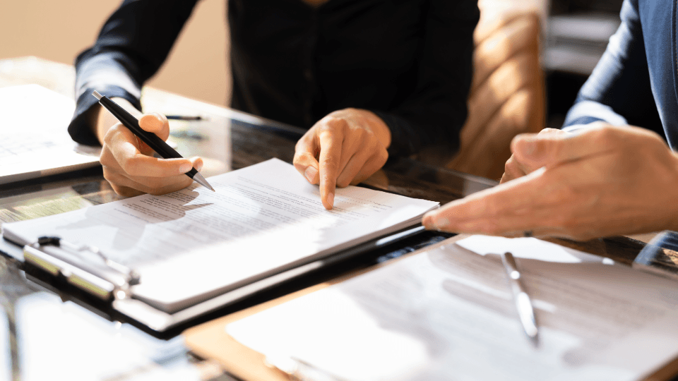 Two people at a desk signing a contract.
