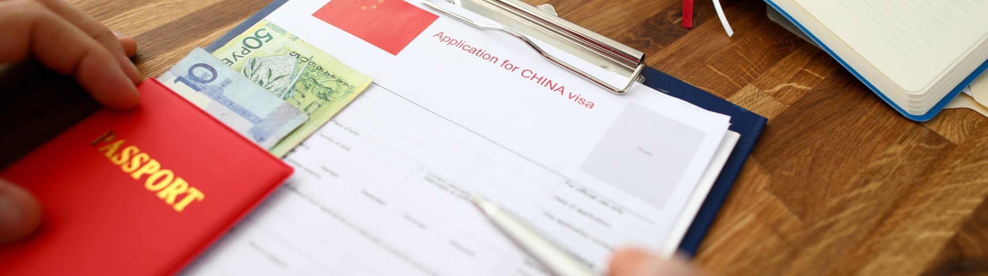 Passport, banknotes and China visa application on a desk