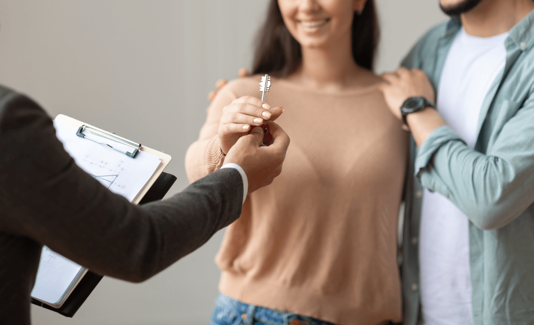 Realtor handing apartment key to couple – symbolic scene of an apartment handover