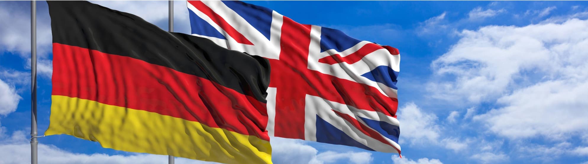 German and UK flags waving side by side against a blue sky, symbolizing customs from the UK to Germany